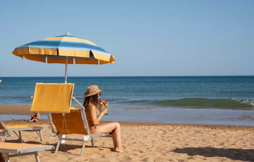 spiaggia modella beve cocktail